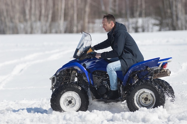 Un bosque de invierno a la luz del día un hombre montando una gran moto de nieve azul