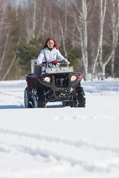 Un bosque de invierno una mujer con pelo de jengibre montando motos de nieve y superando la nieve