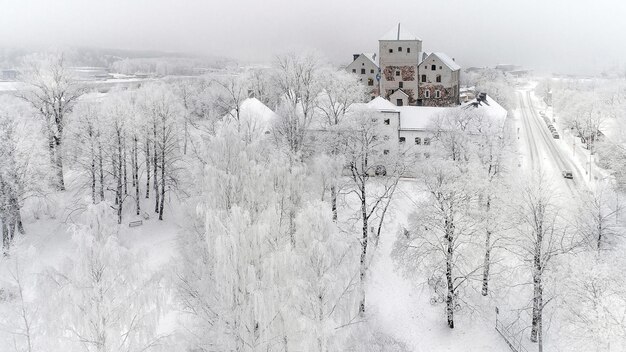 Foto un bosque nevado con un edificio y árboles con un edificio en el fondo