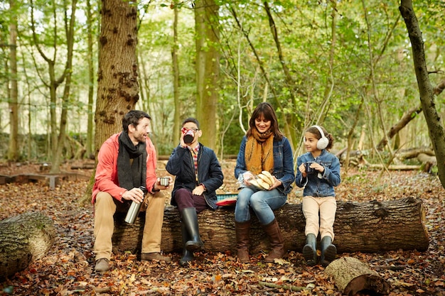 Bosques de hayas en otoño Padres y dos niños sentados en un tronco haciendo un picnic