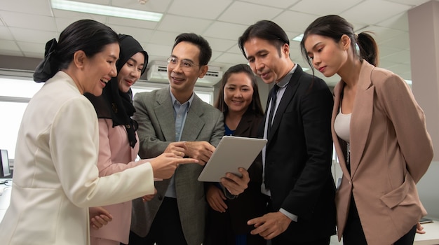 Foto boss explica o projeto por tablet para a equipe de negócios em um escritório moderno.