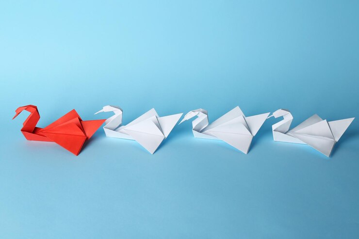 Foto boss vs leader concept pássaros de origami branco atrás de um vermelho sobre fundo azul