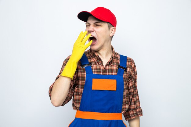 Bostezo cubrió la boca con la mano joven chico de limpieza con uniforme y gorra con guantes