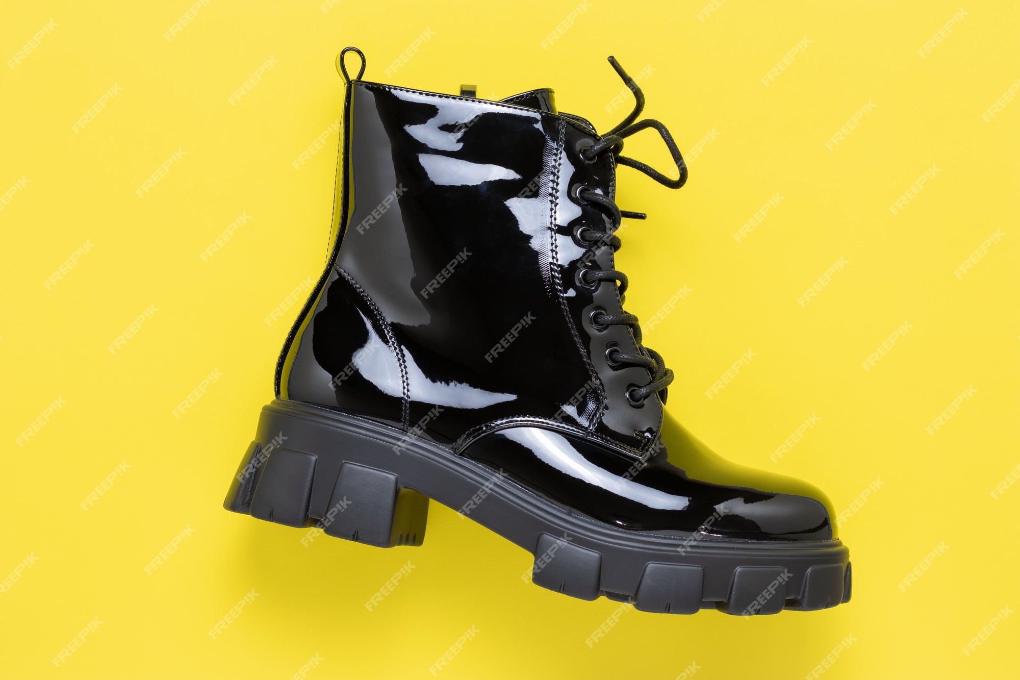 Bota corta negra sobre superficie amarilla. zapatos de charol. zapato de mujer otoño con cordones. botas de exterior modernas en suela de concepto de moda casual. | Foto Premium