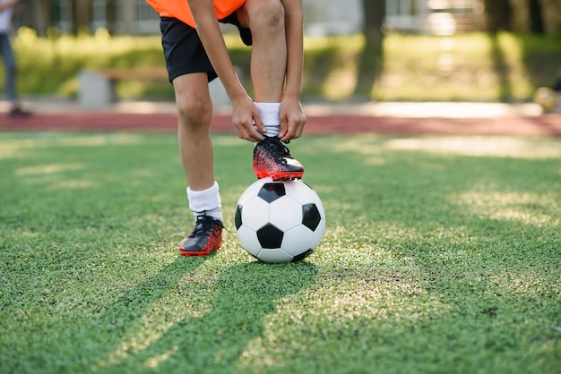 Bota de jogador de futebol que coloca a perna na bola e amarrando o cadarço.