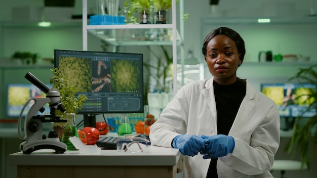 Botanikerin erklärt Botanik-Experiment während eines Online-Videoanrufs, während sie im pharmazeutischen Labor sitzt