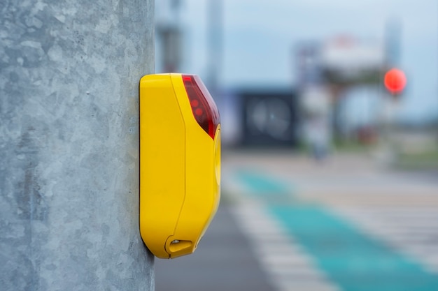 Botão amarelo num semáforo para peões no fundo de uma faixa de pedestres e ciclovias para ciclistas.