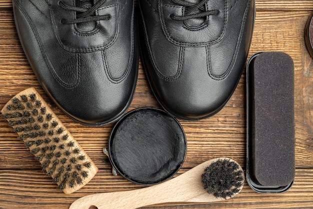 Botas de cuero, cepillos, cera para betún, productos para el cuidado del calzado sobre fondo de madera