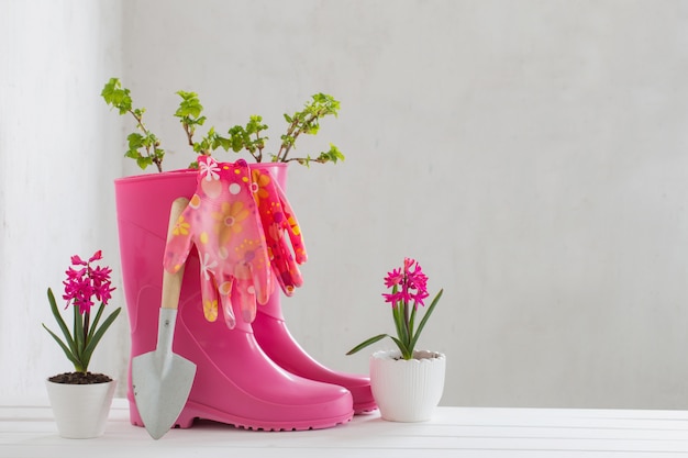 Botas de borracha e flores da primavera na parede branca