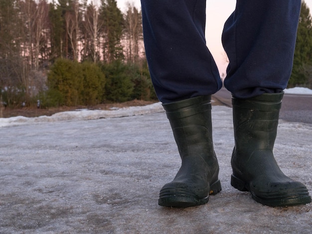 Foto botas de borracha para uso no trabalho um trabalhador da construção civil no asfalto cinza frio lá fora