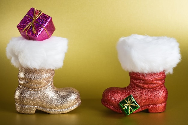 Botas de Papai Noel com caixa de presente em fundo dourado