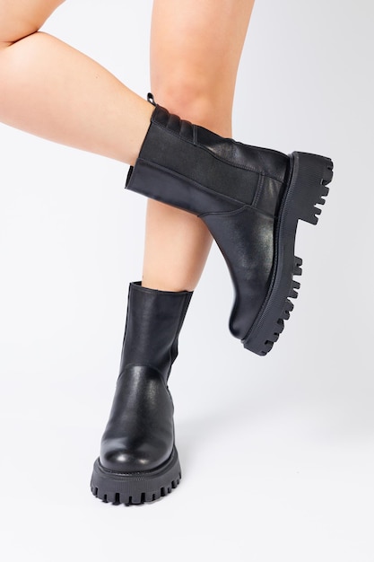 Botas de primavera pretas femininas feitas de couro genuíno estão vestidas com os pés descalços