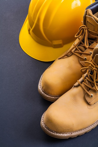 Botas de trabalho e capacete amarelo em fundo preto