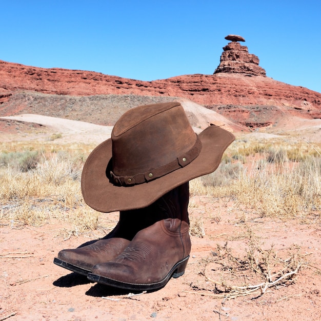 Foto botas e chapéu na frente da famosa pedra mexicana de chapéus