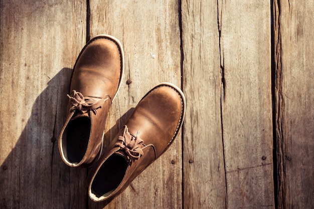 Foto botas elegantes marrons sobre fundo de madeira, cor retrô