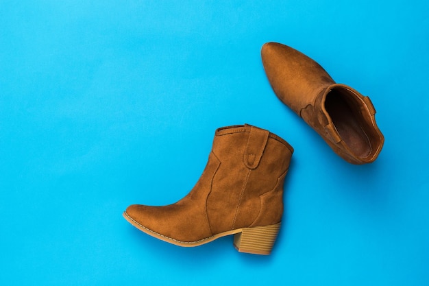 Botas de ante con estilo con tacones sobre un fondo azul. Zapatos de mujer de moda hechos de material natural.