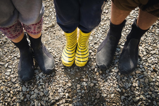 Foto botas de goma para una familia al aire libre. niño y padres en botas de goma cerca del río, primer plano