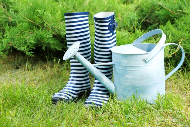 Botas de goma con regadera en el concepto de jardinería de césped