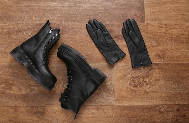 Botas y guantes de cuero negro sobre suelo de madera Vista superior Lay Flat