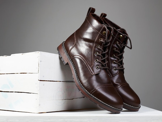 Botas marrones de moda con caja de madera blanca.