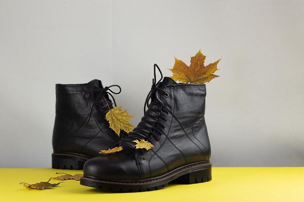 Foto botas marrons de couro sobre fundo amarelo folhas de bordo botas quentes para o frio