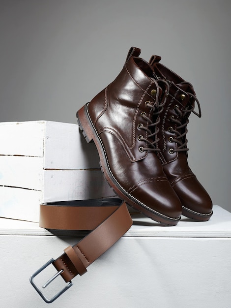 Botas marrons masculinas e cinto na caixa de madeira branca