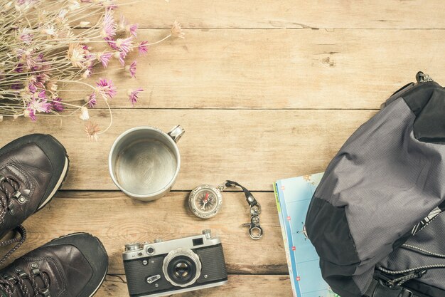 Botas, mochila, brújula y otros equipos de campamento sobre una superficie de madera. El concepto de senderismo en las montañas o el bosque, turismo, tienda de campaña, campamento. Vista plana, vista superior.