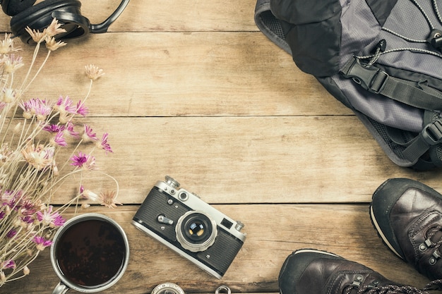 Botas, mochila, brújula y otros equipos de campamento sobre una superficie de madera. El concepto de senderismo en las montañas o el bosque, turismo, tienda de campaña, campamento. Vista plana, vista superior.