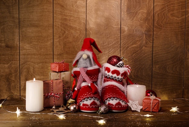 Botas de Navidad tejidas sobre un fondo de madera alrededor de regalos, velas encendidas luces