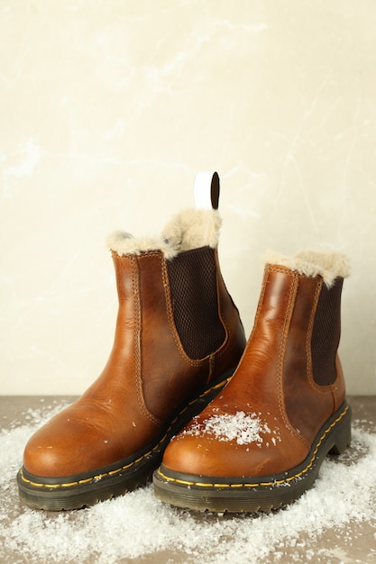 Botas con nieve sobre mesa con textura gris.