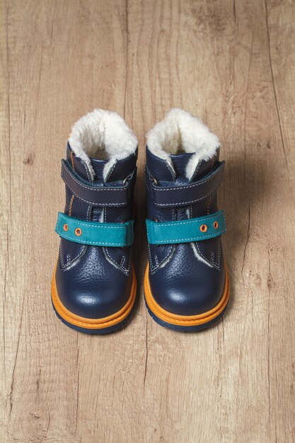 Foto botas de otoño para niños lindos sobre un piso de madera.