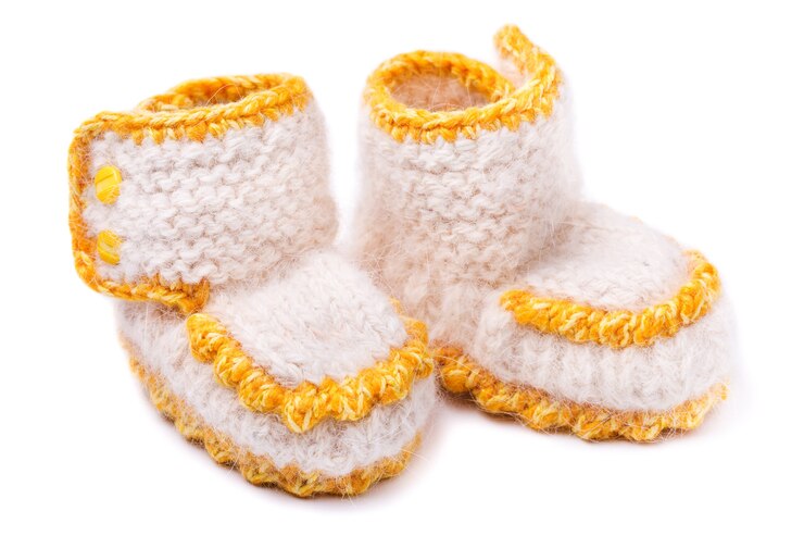 Foto botas para bebês feitas à mão em um fundo branco
