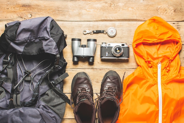 Botas para trilha, binóculos, acessórios de trekking em um fundo de madeira. conceito de caminhadas, turismo, acampamento, montanhas, floresta.