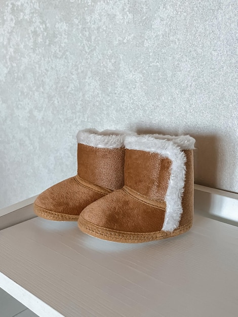 Botas de piel marrón para niños pequeños en el estante de la cómoda moda infantil