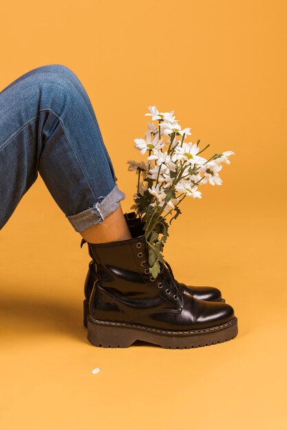 botas de piernas femeninas sentadas con flores en el interior