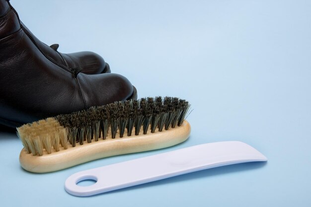 botas pretas com uma escova e um chifre de sapato em um fundo azul