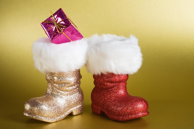 Botas de santa con caja de regalo sobre fondo dorado