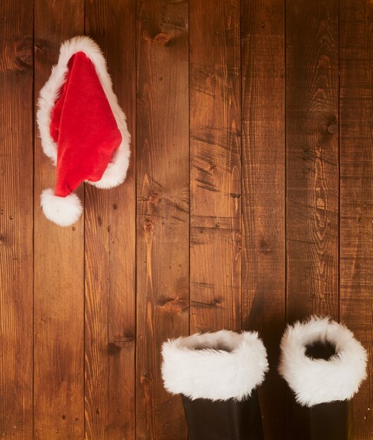 Botas y sombrero de Papá Noel colgado en la pared de madera