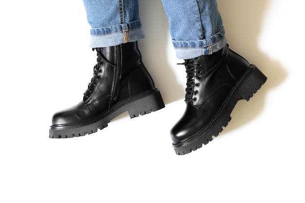 Botas unissex pretas isoladas para inverno e outono com salto bloco de dedo do pé redondo e sola dura em relevo nos pés de alguém com sombras no fundo branco Copiar espaço