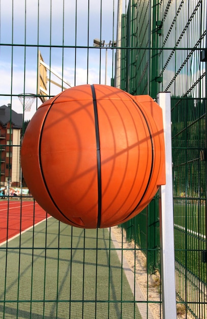 Bote de basura de plástico en forma de pelota de baloncesto en un campo de deportes