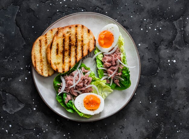 Bote de ensalada romana con atún enlatado y huevo cocido delicioso desayuno tapas merienda en una vista superior de fondo oscuro