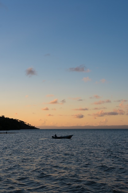 un bote en medio de la bahía con una puesta de sol detrás