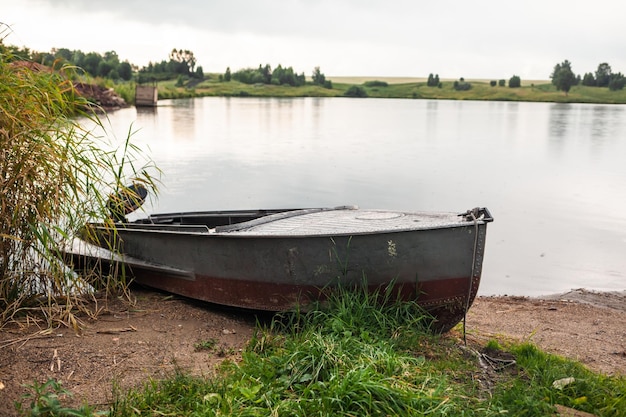 Un bote a motor está estacionado en la orilla de un lago o río por la tarde al atardecer o temprano en la mañana