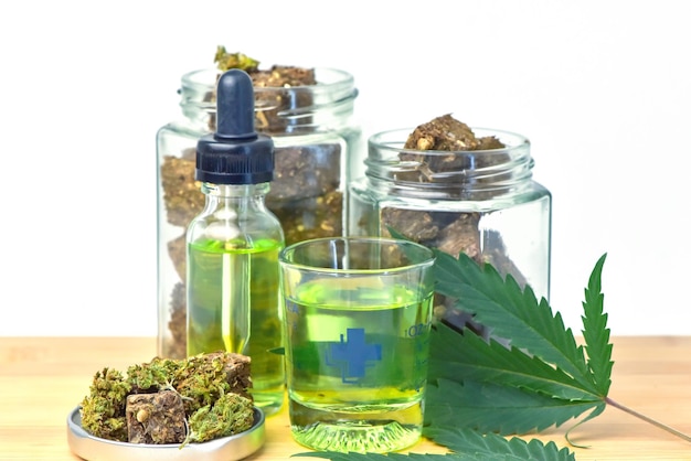 Botella de aceite de cáñamo Frasco de marihuana seca sobre mesa de madera fondo blanco CBD Aceite de cáñamo aceite de cáñamo Productos de marihuana medicinal que incluyen hoja de cannabis cbd y medicina alternativa de aceite de hachís