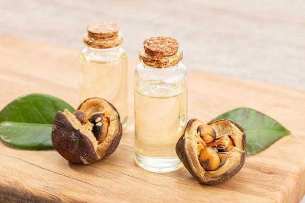 Botella de aceite esencial de camelia y semillas de camelia en mesa de  madera. belleza, cuidado de la piel, bienestar. | Foto Premium