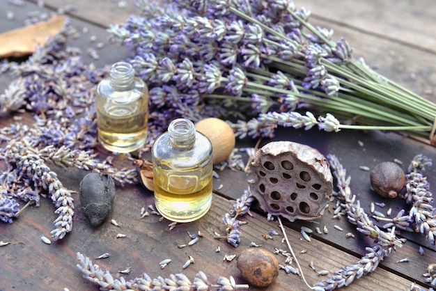 Botella de aceite esencial y flores de lavanda en mesa de madera