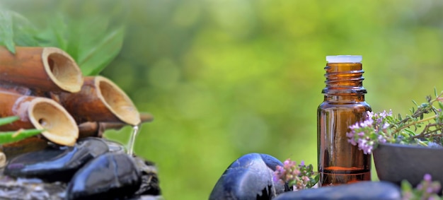 Botella de aceite esencial y fuente de bambú en guijarros