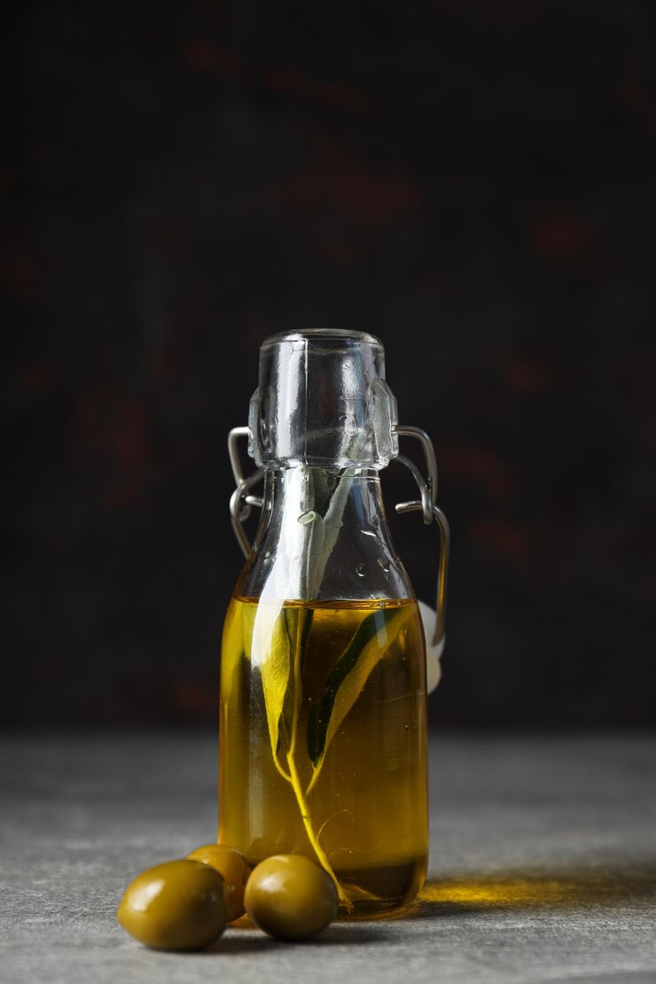 Botella de aceite de oliva y aceitunas sobre fondo oscuro