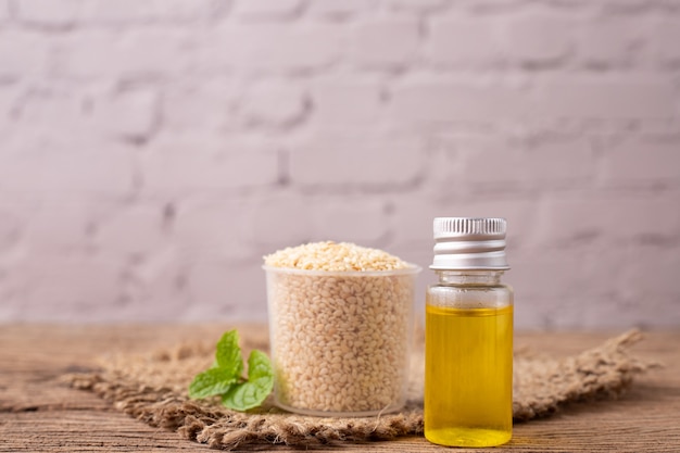 Foto botella de aceite de sésamo blanco sobre mesa de madera.