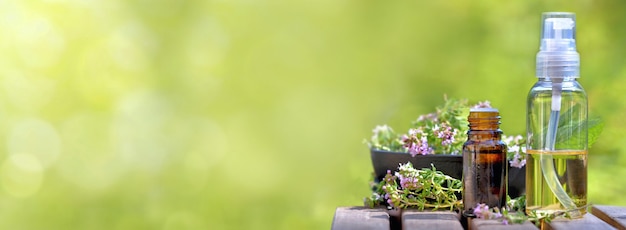 Botella de aceites esenciales derramada sobre una mesa con flores de lavanda sobre fondo verde bokeh